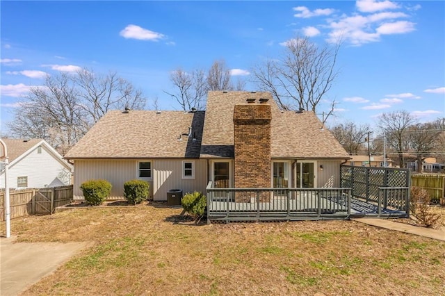 back of property with central air condition unit, a fenced backyard, a yard, roof with shingles, and a chimney