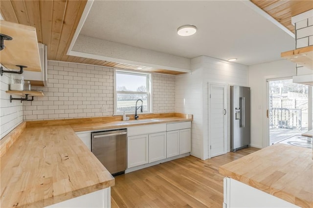 kitchen featuring a sink, a wealth of natural light, appliances with stainless steel finishes, wood counters, and open shelves