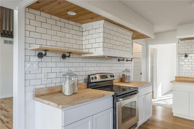 kitchen featuring visible vents, wooden counters, open shelves, decorative backsplash, and stainless steel range with electric stovetop