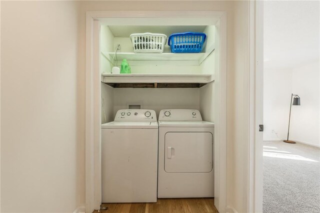 clothes washing area with baseboards, washer and clothes dryer, laundry area, carpet flooring, and wood finished floors