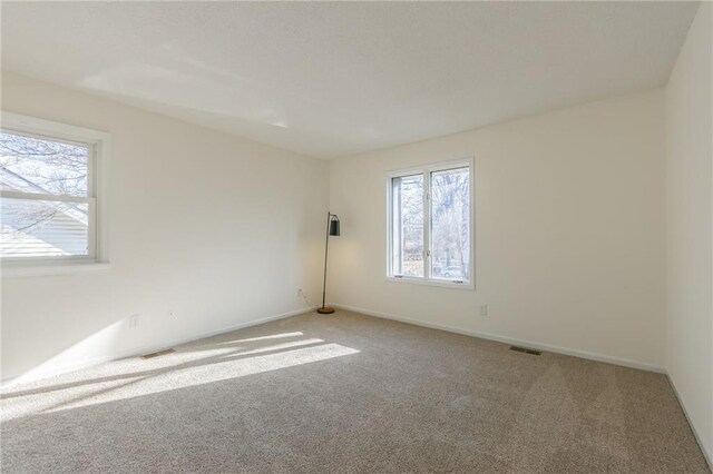 unfurnished room with visible vents, carpet, and baseboards