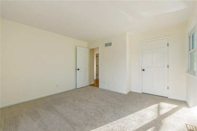unfurnished bedroom with carpet flooring, baseboards, and visible vents