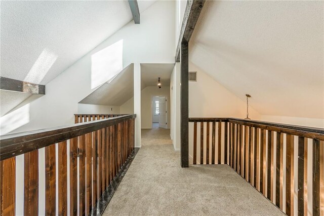corridor featuring lofted ceiling with beams, visible vents, carpet floors, and a textured ceiling