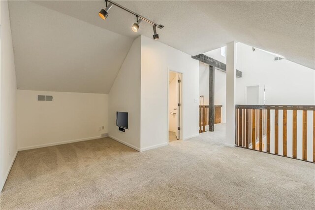 bonus room featuring lofted ceiling, carpet flooring, visible vents, and a textured ceiling