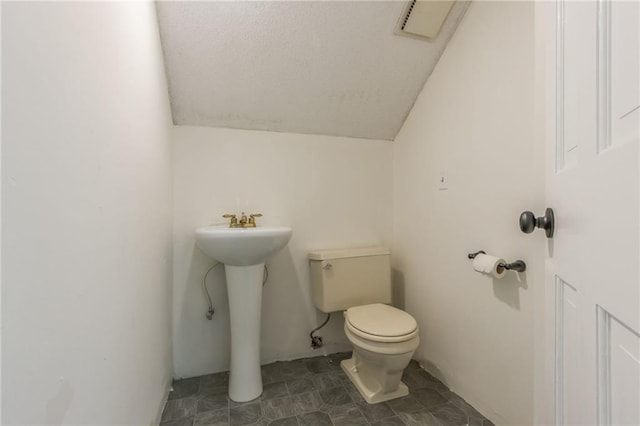bathroom with vaulted ceiling, toilet, visible vents, and a sink