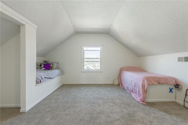 bedroom featuring vaulted ceiling, carpet, visible vents, and a textured ceiling