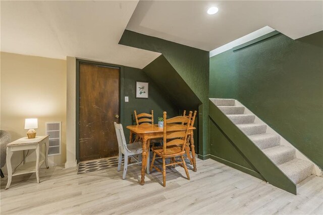 dining area featuring visible vents, wood finished floors, recessed lighting, stairway, and lofted ceiling