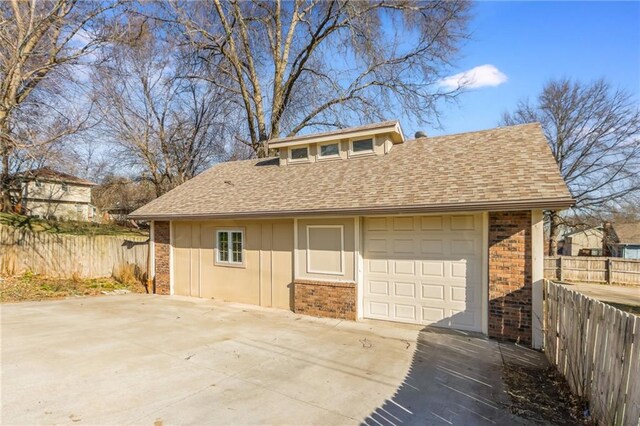 view of front facade featuring brick siding, roof with shingles, and fence