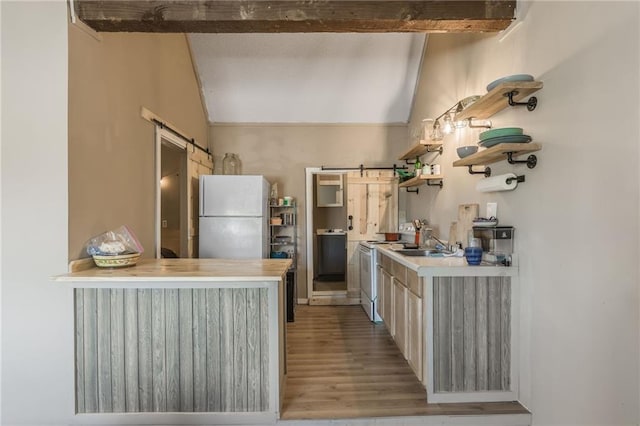 kitchen featuring lofted ceiling with beams, a barn door, white appliances, and light countertops