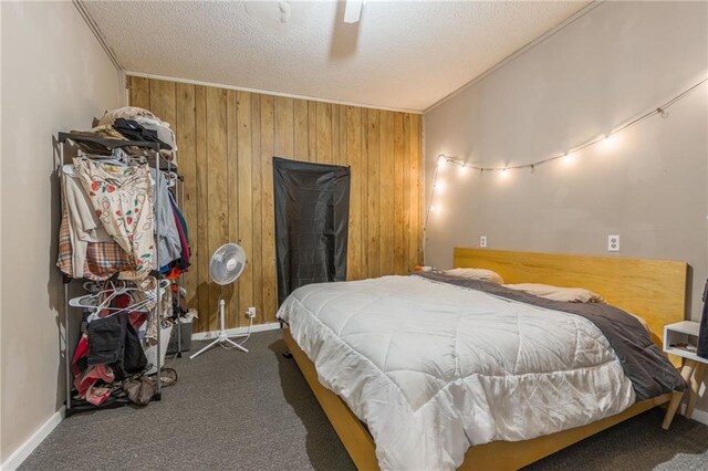 carpeted bedroom featuring baseboards, wooden walls, a ceiling fan, and a textured ceiling