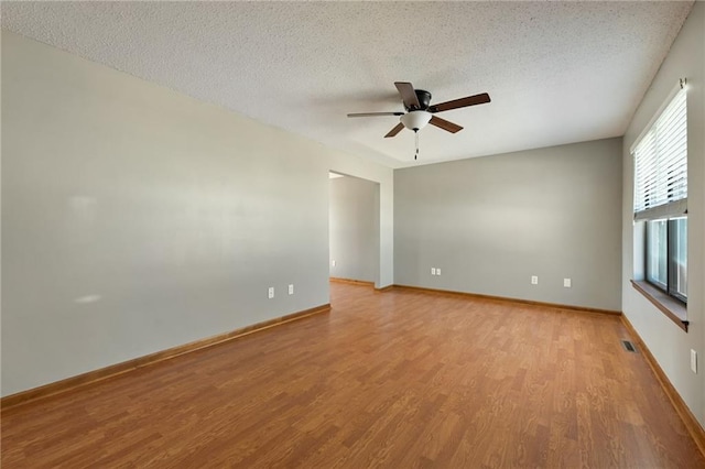 empty room with visible vents, baseboards, light wood-style floors, a textured ceiling, and a ceiling fan