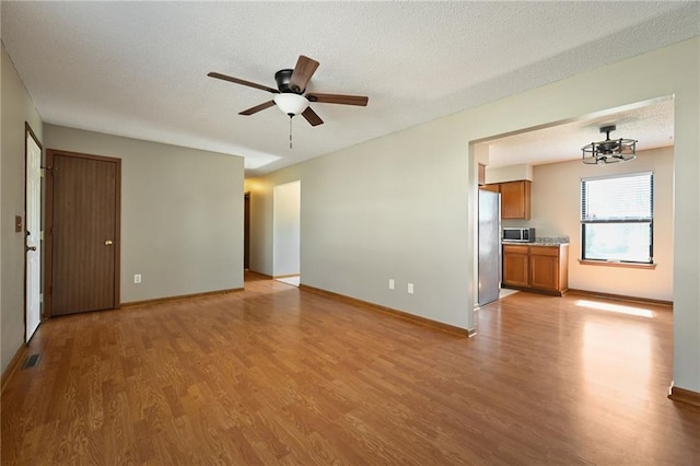 unfurnished living room with a textured ceiling, light wood-style floors, and ceiling fan