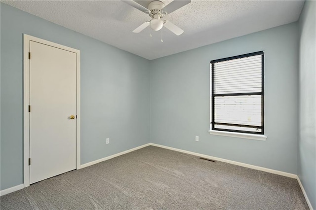 carpeted spare room featuring visible vents, a ceiling fan, baseboards, and a textured ceiling