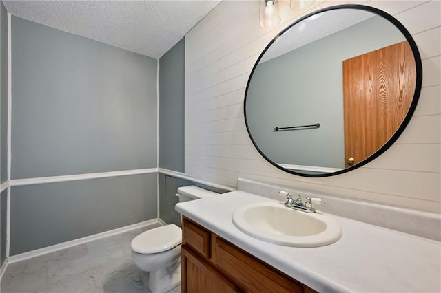 half bathroom featuring a textured ceiling, marble finish floor, vanity, and toilet