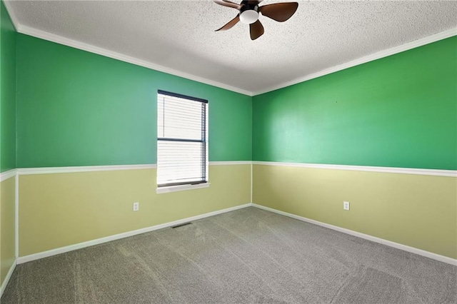 spare room featuring crown molding, baseboards, carpet, ceiling fan, and a textured ceiling