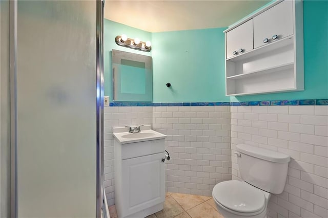 bathroom with tile patterned flooring, toilet, wainscoting, a stall shower, and vanity