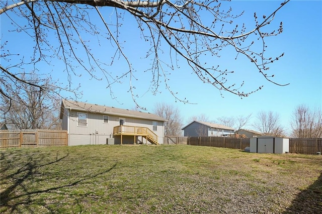 view of yard with a wooden deck, a fenced backyard, stairs, an outdoor structure, and a storage unit