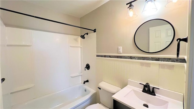 bathroom featuring vanity, toilet, shower / washtub combination, and wainscoting