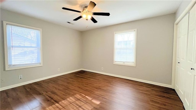 unfurnished bedroom featuring a ceiling fan, visible vents, dark wood-style floors, baseboards, and a closet