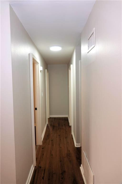 corridor with wood finished floors, visible vents, and baseboards