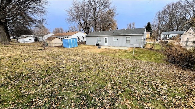 rear view of house with a lawn, a storage shed, an outdoor structure, and fence