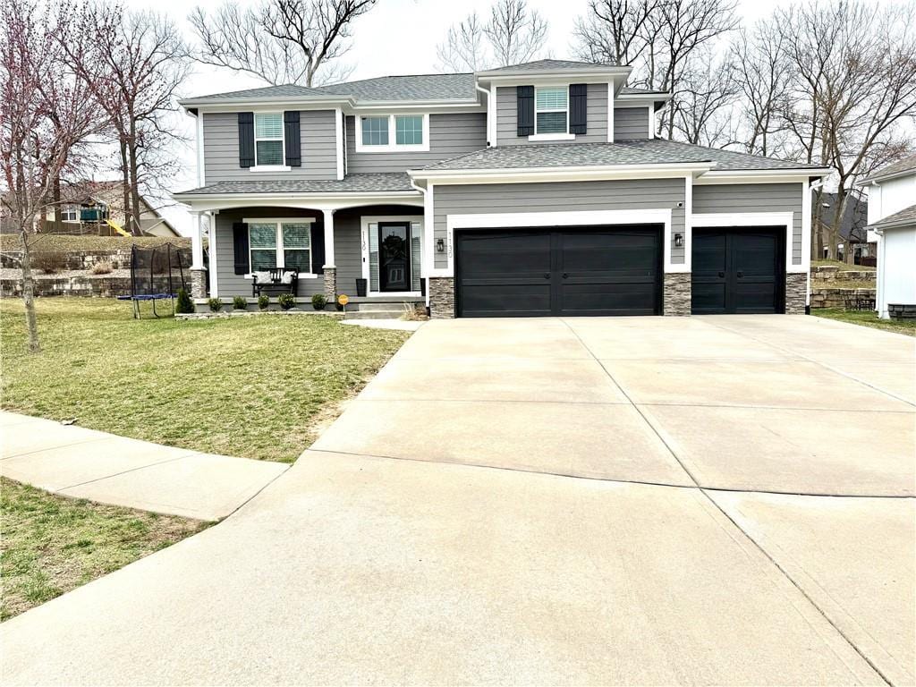 view of front facade with a garage, driveway, a front yard, and a trampoline