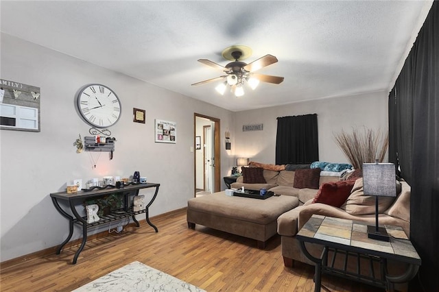 living area featuring baseboards, light wood-type flooring, and ceiling fan