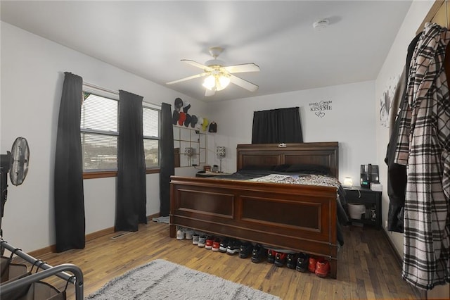 bedroom with baseboards, wood finished floors, and a ceiling fan