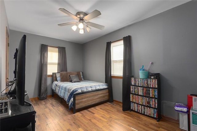 bedroom with light wood finished floors, a ceiling fan, and baseboards