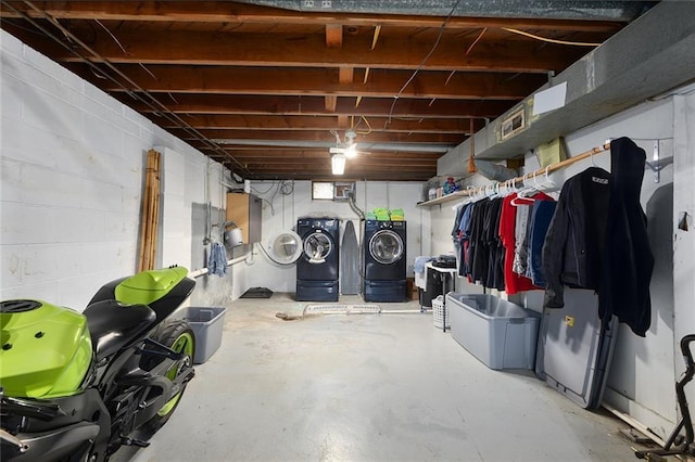 unfinished below grade area with concrete block wall and washer and clothes dryer