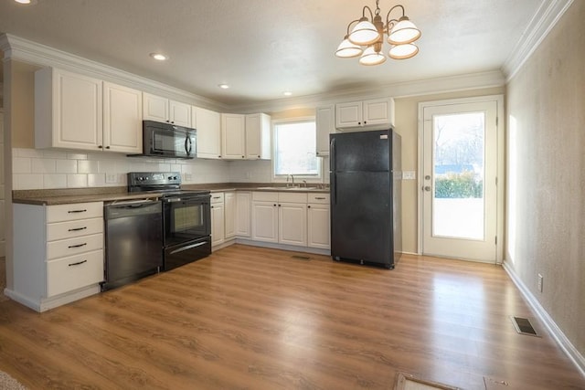 kitchen featuring visible vents, black appliances, ornamental molding, and light wood-style flooring