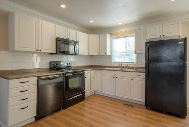 kitchen featuring a sink, black appliances, white cabinets, and light wood finished floors