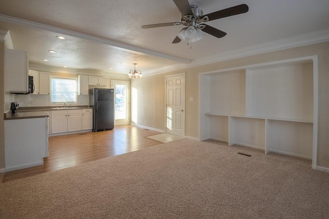 interior space featuring visible vents, crown molding, light carpet, ceiling fan with notable chandelier, and a sink