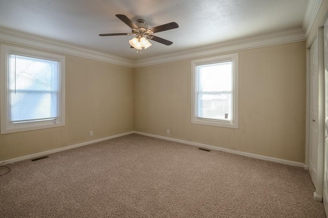 empty room featuring visible vents, crown molding, baseboards, and carpet floors