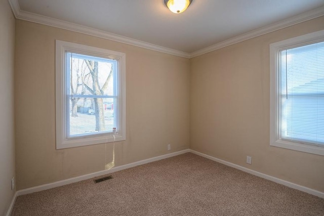 carpeted spare room featuring visible vents, baseboards, and ornamental molding