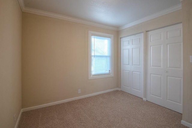 unfurnished bedroom featuring baseboards, carpet, and crown molding