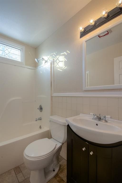 full bath with tile patterned flooring, toilet, wainscoting, bathtub / shower combination, and vanity