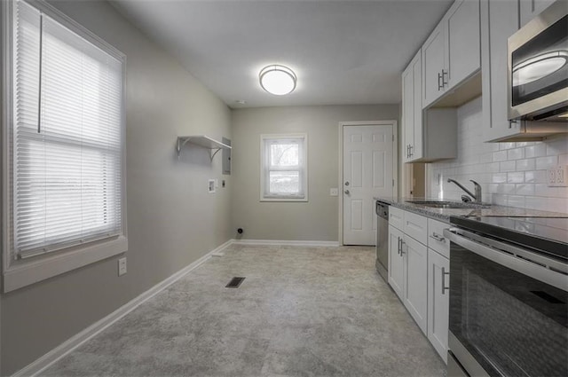 kitchen featuring baseboards, visible vents, a sink, decorative backsplash, and appliances with stainless steel finishes