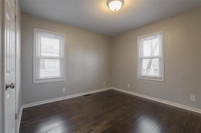 spare room with visible vents, dark wood-style floors, and baseboards