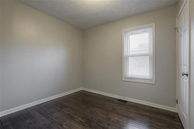 empty room featuring a healthy amount of sunlight, dark wood-style flooring, and baseboards