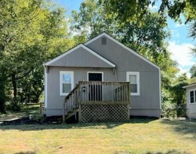 back of property with a wooden deck and a yard