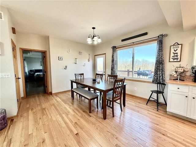 dining area with visible vents, baseboards, light wood-style floors, and an inviting chandelier
