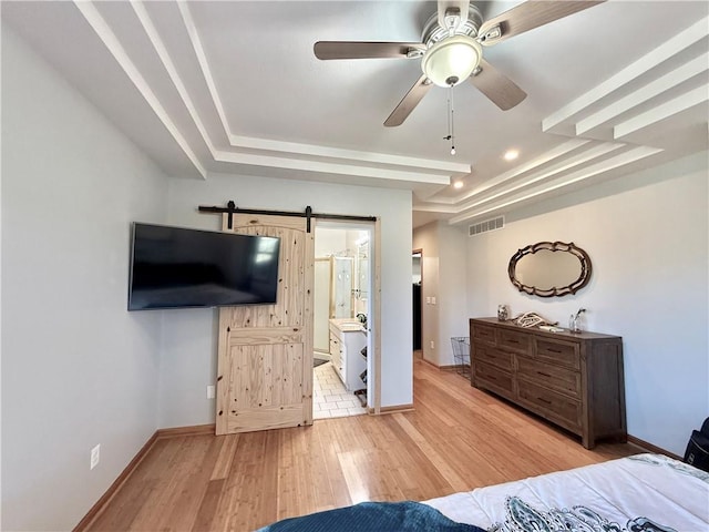 bedroom with baseboards, light wood-type flooring, and a tray ceiling