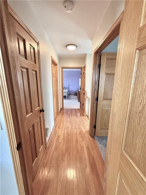 corridor featuring baseboards and light wood finished floors