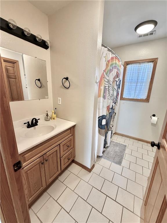 full bathroom featuring a shower with curtain, visible vents, vanity, and baseboards