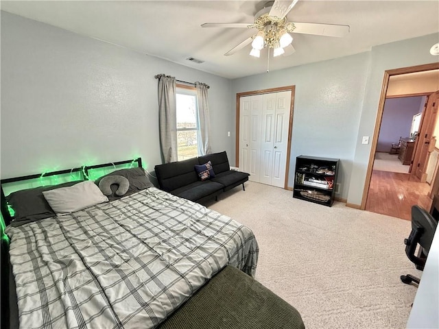 carpeted bedroom with visible vents, baseboards, a closet, and ceiling fan