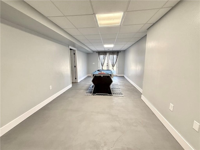 rec room with a paneled ceiling, baseboards, and concrete flooring