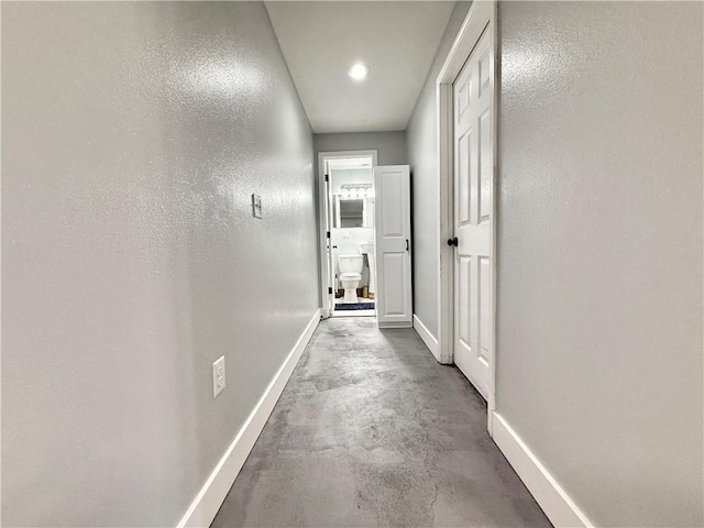 corridor featuring concrete floors and baseboards