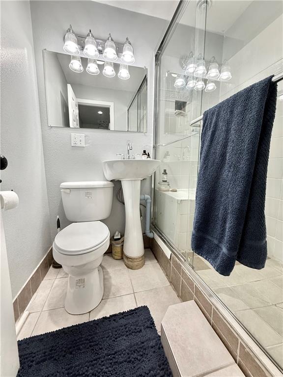 full bath featuring tile patterned floors, toilet, and a stall shower