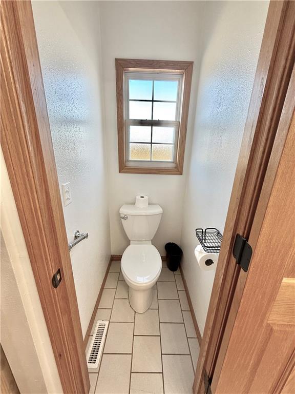 bathroom with tile patterned flooring, toilet, baseboards, and visible vents